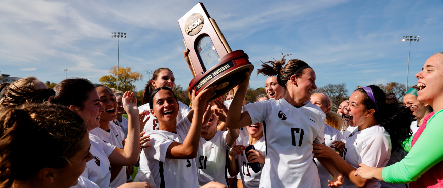 Makena Rietz (17) and Madison Ibale (2) celebrate with teammates by hoisting the NCAA Division II West Region women’s soccer championship trophy.